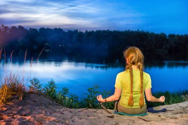 pratik Yoga Nehri üzerinde mavi gökyüzü ile batımını sahilde kadın