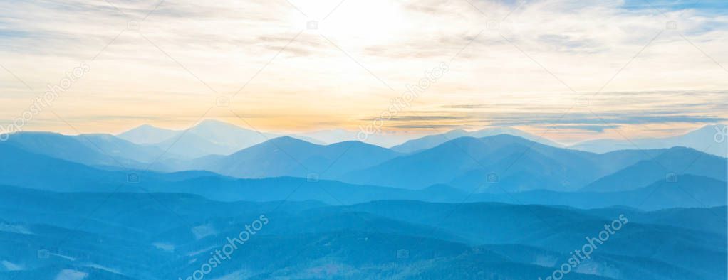 Blue mountains at sunset sky. Panorama view of peaks ridge