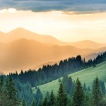 Beautiful sunset in the mountains. Landscape with sun shining through orange clouds