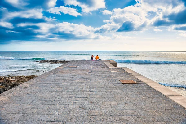 Couple people sitting on stone pier — Stock Photo, Image