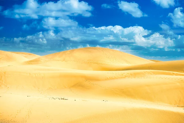 Desert with sand dunes and clouds on blue sky
