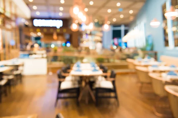 Row of empty dinner tables decorated with tablecloths and napkins in cozy restaurant