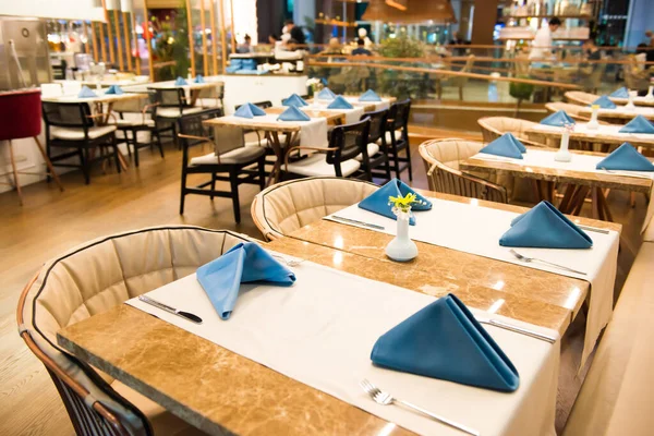 Lokantada masa örtüleri ve peçetelerle süslenmiş boş yemek masaları.