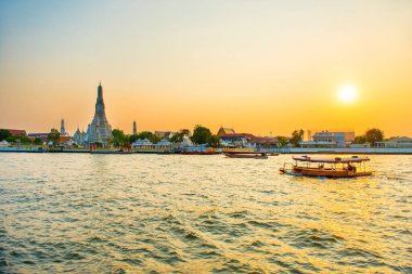 Güzel Şafak Tapınağı ya da Wat Arun manzarası ve güneş batarken Chao Phraya Nehri 'nde kayıklar. Bangkok, Tayland
