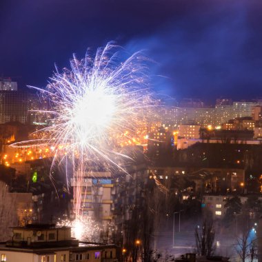 Mavi gece gökyüzünün olduğu bir şehirde bayram havai fişekleri