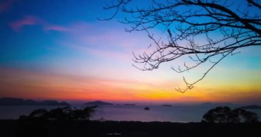 Dramatik gökyüzü ve renkli bulutlarla dağdan denize güzel bir gün doğumu zamanı. Koh Lanta Adası, Tayland. 4K zaman aşımı klibi