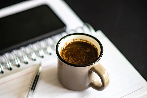 テーブルの上にコーヒー 携帯電話やノートパッドのカップで宿題のコンセプト — ストック写真