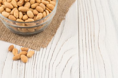 Eski ahşap masa üzerinde bir cam kase tuzlu fıstık. 