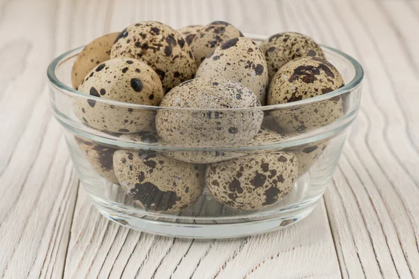 Quail eggs in a glass bowl on old white wooden table. — Stock Photo, Image