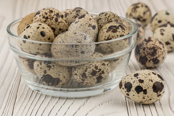 Quail eggs in a glass bowl on old white wooden table. — Stock Photo, Image