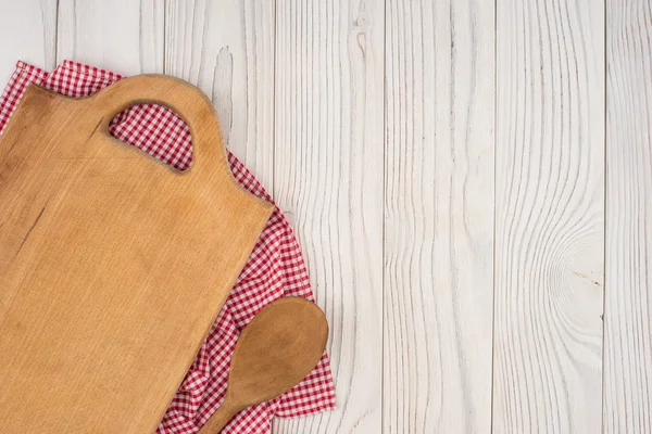 Tábua de corte e uma colher em um guardanapo de cozinha na velha mesa de madeira — Fotografia de Stock
