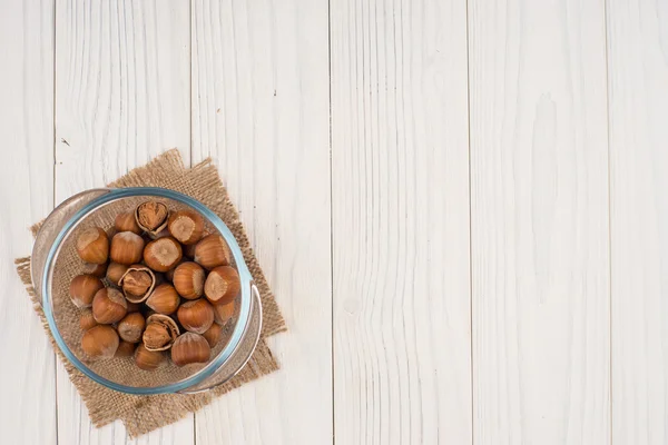 Nocciola in una ciotola di vetro su un vecchio tavolo di legno bianco . — Foto Stock