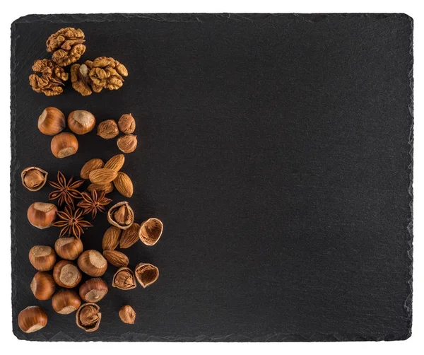 Nuts mix on a black slate board. Isolated on white background. — Stock Photo, Image
