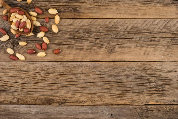 Amendoim em colheres de madeira em um velho fundo de madeira . — Fotografia de Stock