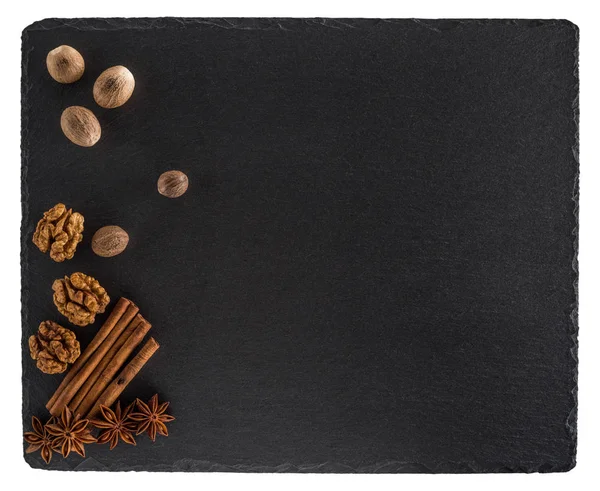 Nutmeg, walnuts, cinnamon and star anise on a black slate board. — Stock Photo, Image