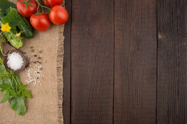 Tomates frescos con pepinos sobre una vieja mesa de madera oscura . —  Fotos de Stock