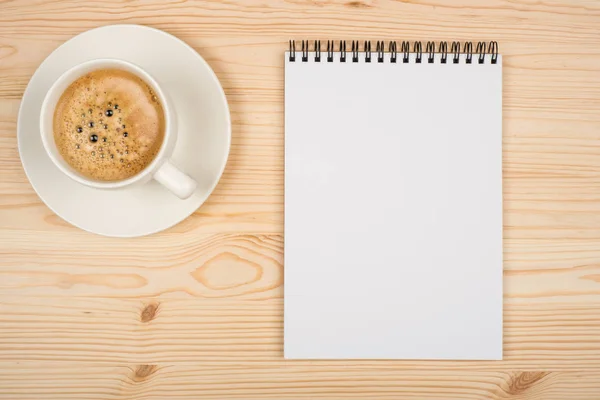 Coffee cup, spiral notebook on the wooden table — Stock Photo, Image