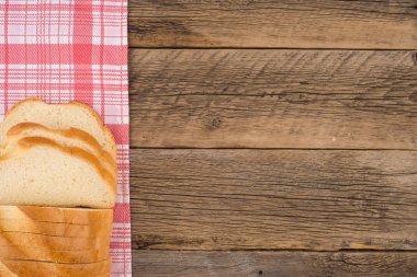 Eski bir ahşap masada ekmek dilimlenmiş.