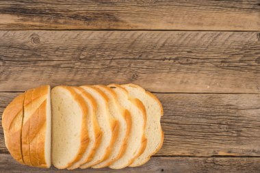 Eski bir ahşap masada ekmek dilimlenmiş.