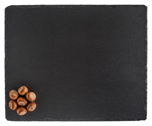 Hazelnuts on a black slate board. Isolated on white background. — Stock Photo, Image
