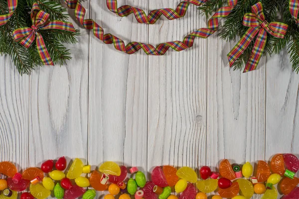 The branch of spruce with colored candies on the old white woode — Stock Photo, Image