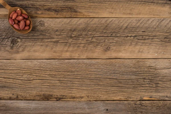 Amendoins em colher de madeira em um velho fundo de madeira . — Fotografia de Stock
