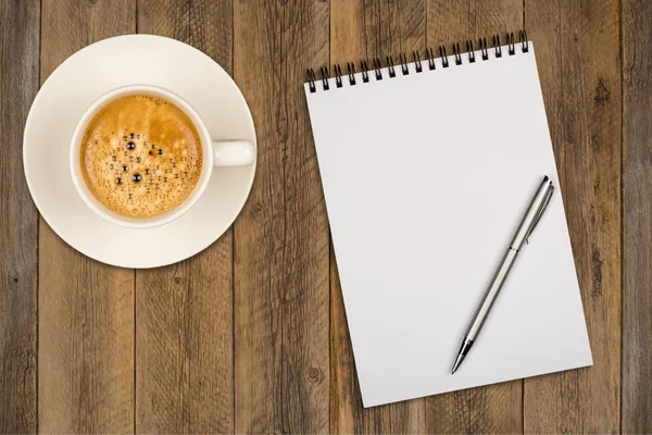 Coffee cup, spiral notebook and pen on the wooden table — Stock Photo, Image