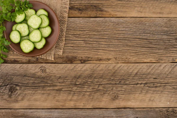 Cutting cucumbers on a plate and old wooden table. — Stock Photo, Image
