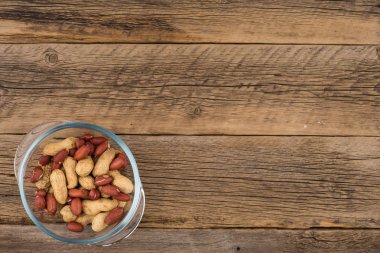 Eski ahşap masa üzerinde bir cam kasede soyulmuş fıstık. 