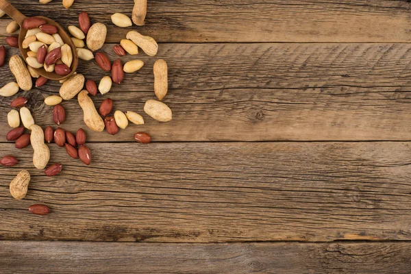 Amendoins em colher de madeira em um velho fundo de madeira . — Fotografia de Stock