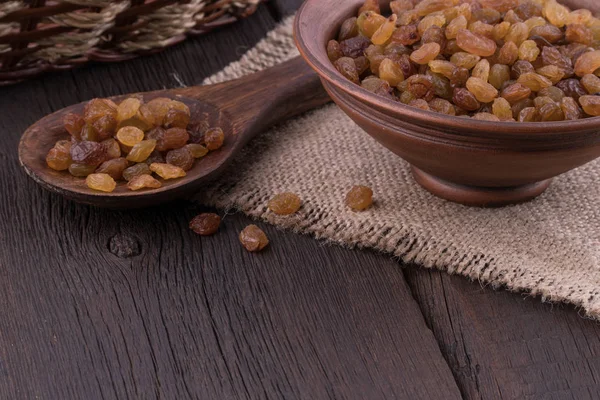 Raisins in a ceramic bowl on old wooden table. — Stock Photo, Image