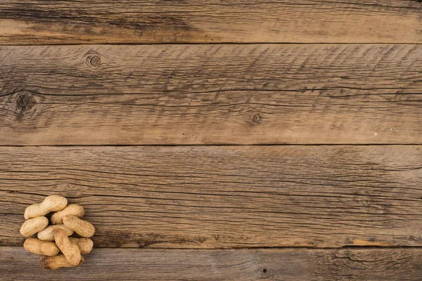Cacahuetes en la cáscara sobre una vieja mesa de madera . —  Fotos de Stock