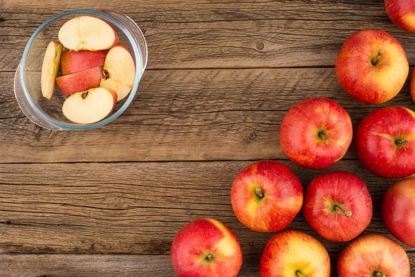 Elma eski ahşap masa üzerinde bir cam kase dilimlenmiş. 