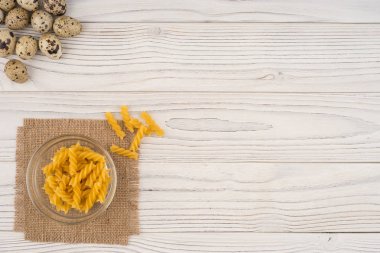 Eski ahşap masa üzerinde bir cam kapta makarna. 