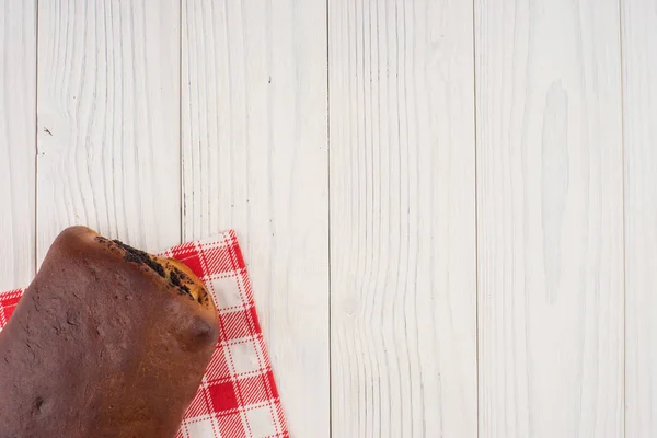 Bollo con semillas de amapola en una servilleta de cocina y una vieja mesa de madera — Foto de Stock