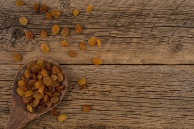 İçinde eski ahşap masa üstünde tahta kaşık kuru üzüm. 