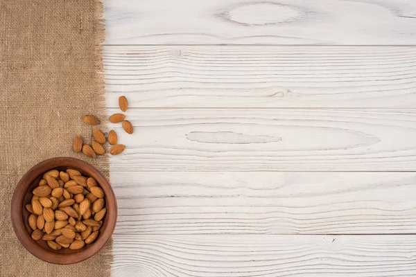 Almendras en un bol marrón y mesa de madera blanca vieja . —  Fotos de Stock