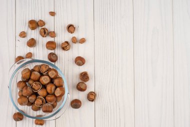 Eski ahşap masa üzerinde bir cam kase fındık. 