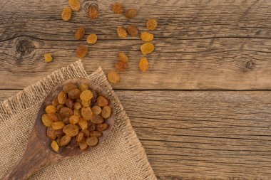 İçinde eski ahşap masa üstünde tahta kaşık kuru üzüm. 