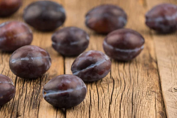 Fresh plums on a dark wooden table. — Stock Photo, Image
