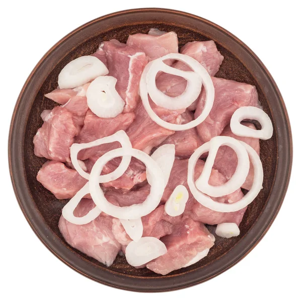 Rohes Fleisch in Stücke geschnitten mit Zwiebeln auf einem braunen Teller. — Stockfoto