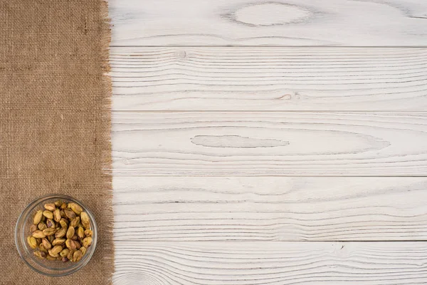 Nozes de pistache em uma tigela de vidro em uma mesa de madeira branca velha . — Fotografia de Stock