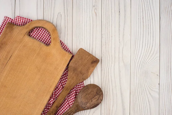 Cutting board and a spoon, spatula on a kitchen napkin on old wo — Stock Photo, Image