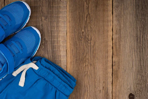 Kinder-Sporthose mit Turnschuhen auf einem Holztisch. — Stockfoto