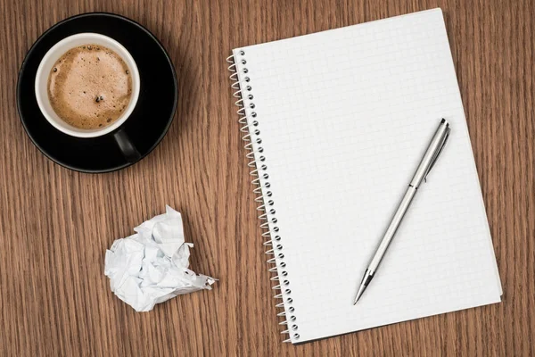 Coffee cup and blank notepad over wooden table. — Stock Photo, Image