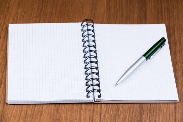 Pen en notitieblok op een houten bureau. — Stockfoto