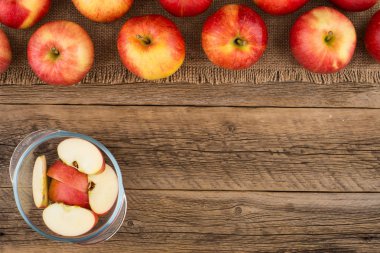 Elma eski ahşap masa üzerinde bir cam kase dilimlenmiş.