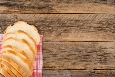 Eski bir ahşap masada ekmek dilimlenmiş.