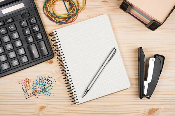 Calculator notebook and pen on a wooden office desk. — Stock Photo, Image