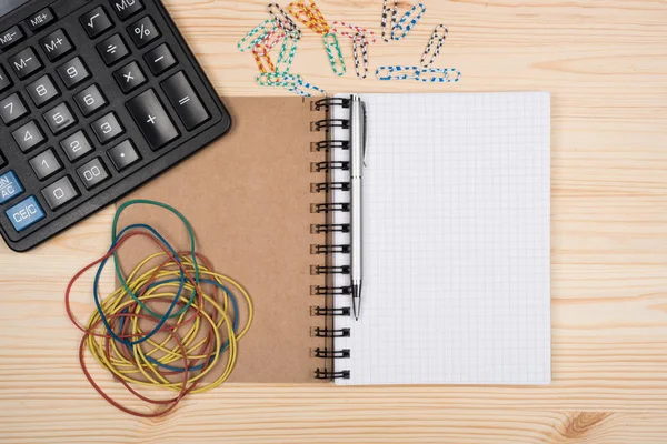 Calculator notebook and pen on a wooden office desk. — Stock Photo, Image